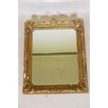 A C19th wall mirror in a gilt swept frame, carved wood and gilded gesso with some losses, hanging