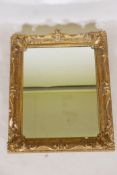 A C19th wall mirror in a gilt swept frame, carved wood and gilded gesso with some losses, hanging