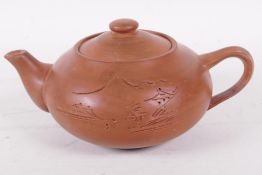 A Chinese Yixing pottery teapot engraved with a mountain landscape, 7" long