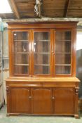 A C19th cabinet bookcase, the upper section with three glazed doors and fitted shelves, over a two