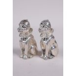 A pair of silver plated condiments in the form of dogs wearing cricket caps, 2½" long