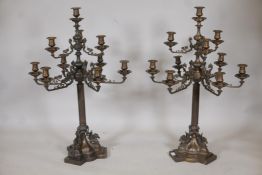 A pair of nine branch bronze candelabra, the arms with ram's mask decoration, raised on a reeded