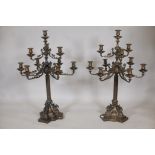 A pair of nine branch bronze candelabra, the arms with ram's mask decoration, raised on a reeded