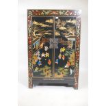 A Chinese black lacquer cabinet, the doors with painted and gilt decoration of children playing in a