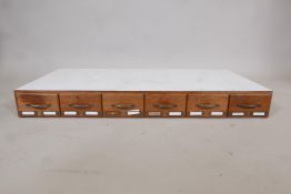 A rack of six filing drawers with mahogany fronts and brass handles, each drawer divided for storage