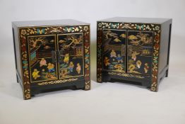 A pair of Chinese black lacquer bed side chests, the doors with painted and gilt decoration of