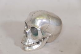 A white metal model of a skull with articulated jaw, 4" high
