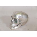 A white metal model of a skull with articulated jaw, 4" high