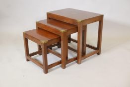 A nest of three military style mahogany coffee tables with brass cap corners on square supports, 19"