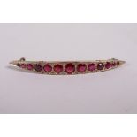 A yellow metal bar brooch set with graduated garnets, probably 9ct, 2" long