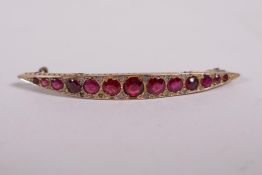 A yellow metal bar brooch set with graduated garnets, probably 9ct, 2" long