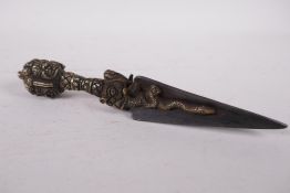 A Tibetan bronze phurba, the handle decorated with wrathful deity masks, 9" long