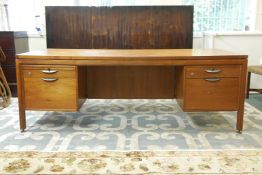 A 1970s teak kneehole desk, each bank of drawers fitted with a slide and filing drawers, possibly