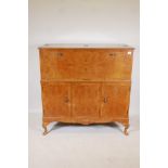 A C20th walnut veneered cocktail cabinet with cantilever front revealing a mirrored interior, over