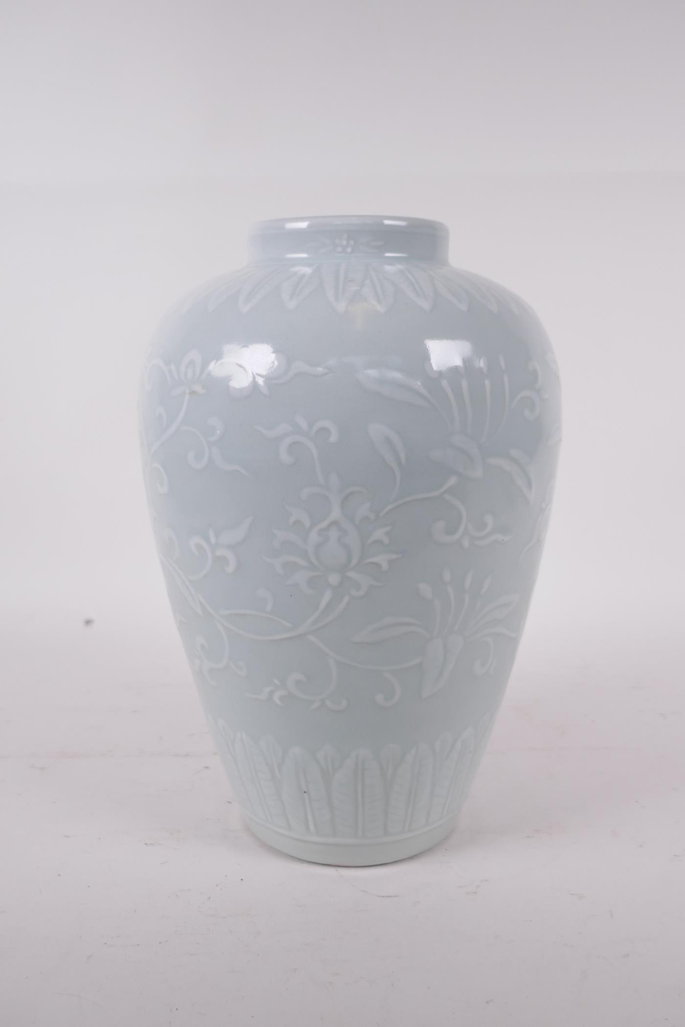 A celadon glazed porcelain jar with raised underglaze lotus flower decoration, incised six character