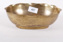 A Chinese brass shaped rim bowl engraved with a bird amongst flowers, the base with two dragons