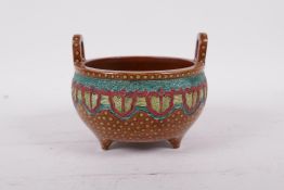 A Chinese two handled pottery censer raised on tripod supports, with bright enamel decoration,