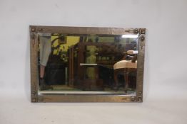 An Arts and Crafts brass framed wall mirror with bevelled glass plate, in the manner of Liberty, 37"