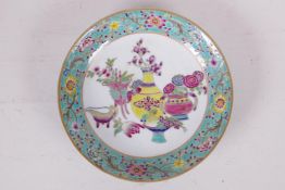 A famille rose porcelain cabinet dish decorated with objects of virtue within a floral border,