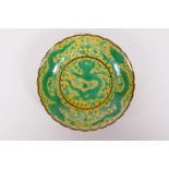 A Chinese yellow ground porcelain saucer with a shaped rim and green dragon decoration, Qian long