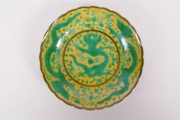 A Chinese yellow ground porcelain saucer with a shaped rim and green dragon decoration, Qian long