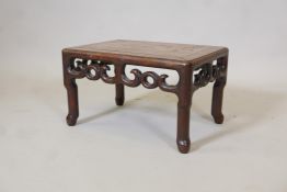 A Chinese rosewood low table/stande with scrolling pierced frieze, raised on shaped supports,