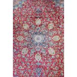 A red ground Isfahan carpet with a Persian floral pattern and blue borders, 94" x 130"