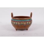 A Chinese two handled pottery censer raised on tripod supports, with bright enamel decoration,