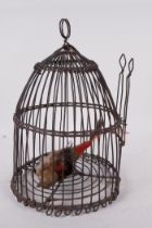 A domed wire bird cage with woven banding, housing a model bird with metal head and feet, 11" high