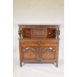 A 1930s oak court cupboard, the upper section with single cupboard, the base with two drawers over