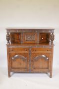 A 1930s oak court cupboard, the upper section with single cupboard, the base with two drawers over