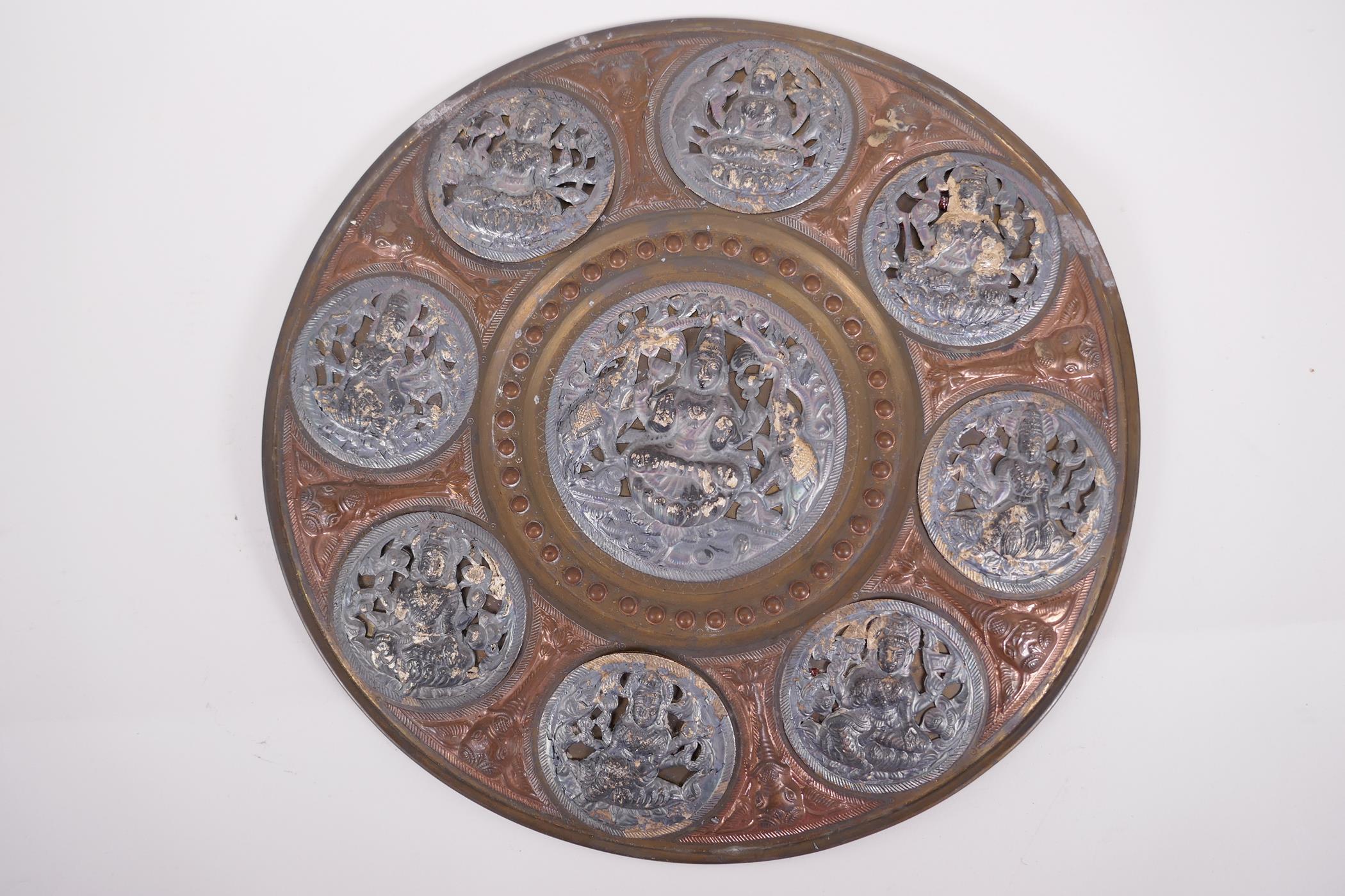 An Indian Tangore copper and brass wall plaque decorated with pressed and pierced white metal