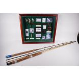 A cased display of fishing ephemera and two vintage 7' fly fishing rods