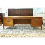 A 1970s teak kneehole desk, each bank of drawers fitted with a slide and filing drawers, possibly