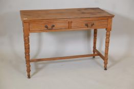 A satin walnut two drawer writing table on ring turned supports and plain stretchers, 29" high,