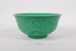 An apple green glazed porcelain rice bowl with raised dragon decoration, six character mark to base,