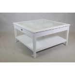 A painted coffee table with push-pull drawer and glass top, raised on tapering supports united by an