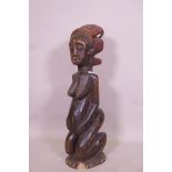 An antique African carved wood fertility figure with beaded headdress and inset with sea shells,