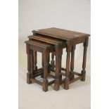 A nest of three oak occasional tables, raised on turned column supports, 19" x 13" x 19"