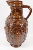 A treacle glazed earthenware jug embossed with biblical figures, 17½" high