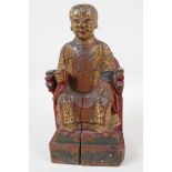 A Chinese carved wood figure of a dignitary seated on a throne, traces of paint, 9" high