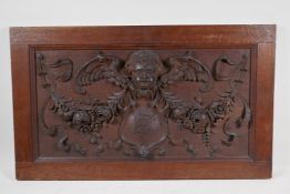 A C19th carved oak panel with raised cherub, floral garland and heraldic shield decoration, 29" x