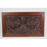 A C19th carved oak panel with raised cherub, floral garland and heraldic shield decoration, 29" x