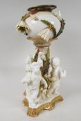 A C19th porcelain oil lamp base supported by three cherubs, the bowl encrusted with flowers in the