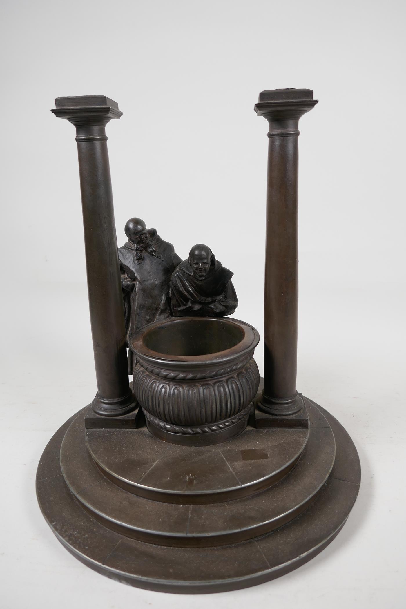 A bronze stand cast as two classical figures looking into a well, 10" diameter, 11" high