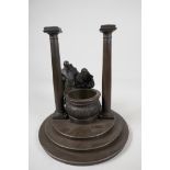 A bronze stand cast as two classical figures looking into a well, 10" diameter, 11" high