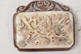 An oriental carved wood and bone pendant carved with birds in a flowering tree, 2½" long, signed