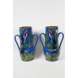 A pair of Devon pottery two handled red ware vases painted with parrots in a tree, 10" high