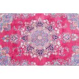 A pink/red ground Persian Kashmar carpet with a floral medallion design, 77" x 117"