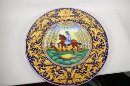 An Italian fayence pottery charger, painted with a horseman and his dog, within an elaborate '